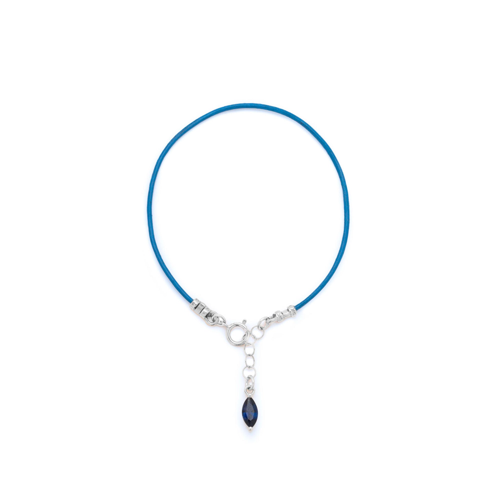 A delicate blue cord bracelet with a silver clasp and a dangling dark blue teardrop crystal charm, shown on a plain white background.